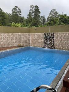 a large swimming pool with a stone wall at Villa Sibolangit Satu Hati near Hillpark with private pool in Bandarbaru