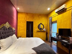 a bedroom with a bed and a tv and yellow walls at 沐-湯宿溫泉行旅 in Jiaoxi