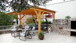 a wooden pavilion with chairs and a table and a fireplace at Apartments Happy Day in Karlobag