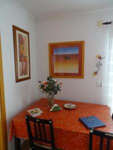 Una mesa con un mantel rojo y un jarrón de flores. en Ferienwohnung Meerblick Atalaia, en Lourinhã