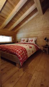 Un dormitorio con una cama en una cabaña de troncos en Demi-Chalet Savoyard, en Le Petit-Bornand-lès-Glières