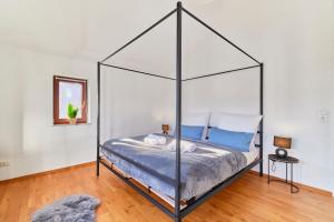a bedroom with a canopy bed with blue pillows at Traumferienwohnung Domblick - Parkplatz inklusive, zentral mit Altstadtblick & Netflix in Limburg an der Lahn
