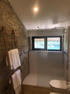 een badkamer met een douche, een toilet en een raam bij Sobreiro Valley - Casa Isabel in Vieira do Minho