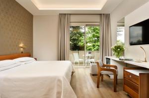 una camera d'albergo con letto, scrivania e TV di Hotel Continental Wellness & Spa a Sirmione