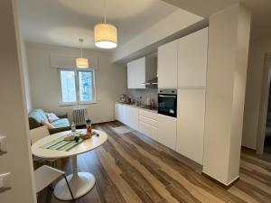 a kitchen with white cabinets and a table in a room at Rainbow Luxury Home Bari in Bari