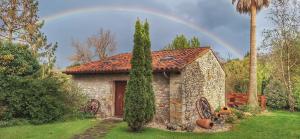 un arco iris sobre una casa de piedra con un árbol en Palación de Toñanes en Toñanes