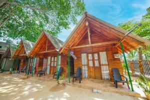 una piccola casa in legno con sedie di fronte di Cool Banyan Cabana a Trincomalee