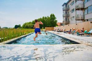 un hombre saltando a una piscina en West Bay Apartments, en Middelkerke