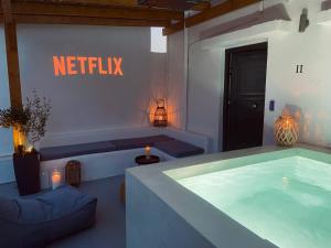 埃尔莫波利斯AVALON Luxury Suites的房间里有一个热水浴缸，上面有写着“Netflix”的标志