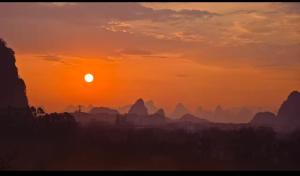 a sunset with the sun setting over the vimy rocks at Guilin Village Creek Inn in Guilin