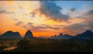 a sunset with mountains in the background at Guilin Village Creek Inn in Guilin