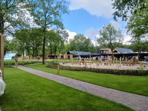 un parque con bancos y mesas en el césped en Ruime en comfortabele bungalow aan bosrand, en Lage Mierde