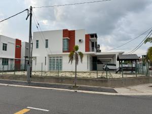 a white house with a palm tree in front of a street at Acik Homestay in Pokok Sena