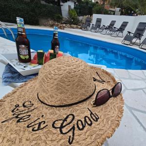 a straw hat and sunglasses sitting next to a pool at Villa Adria in Novalja