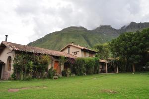 ein Haus auf einem Feld mit einem Berg im Hintergrund in der Unterkunft Valle Dorado Lodge in Cusco