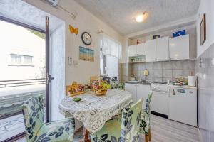 uma cozinha com uma mesa com cadeiras e uma mesa e uma mesa e uma cozinha em Apartments Cindrić em Selce