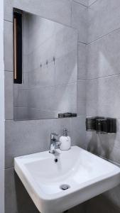 a bathroom with a white sink and a mirror at Tatami with HomeCinema, 9pax, Urban Suites by PG Home in George Town