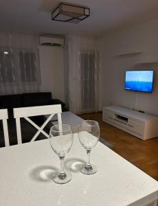 due bicchieri da vino seduti su un tavolo in soggiorno di Apartment Shine a Podgorica