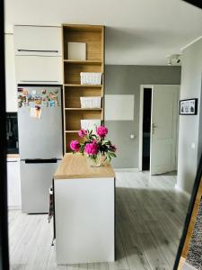a kitchen with a refrigerator and a counter with flowers on it at Apartament Mistral 2 in Pogórze +9 photos