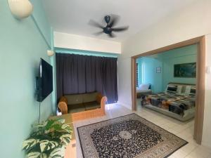 ein Wohnzimmer mit einem TV, einem Sofa und einem Bett in der Unterkunft PD Seaview Paradise Lagoon Apartment in Port Dickson