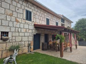a stone building with a patio with a table and chairs at Antini dvori in Imotski