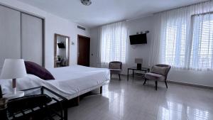 a bedroom with a bed and chairs and a television at Atrium Hotel in Bolnuevo