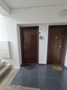 zwei braune Türen in einem Zimmer mit Fliesenboden in der Unterkunft Egi's Apartment in Shkodra