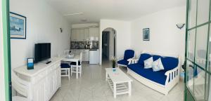uma sala de estar com um sofá azul e uma cozinha em -MONTORIAN Apartments -LANZAROTE em Tías