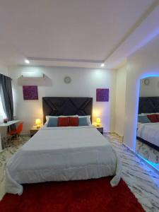 1 Schlafzimmer mit einem großen weißen Bett und 2 Tischen in der Unterkunft Professionals & Family Friendly with Work Stations PS5 & near Beaches B11 Ivy Lux2 in Lagos