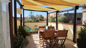 patio con tavolo e sedie sotto un ombrellone giallo di Appartamento La Terrazza - Località Cala Gavetta a La Maddalena