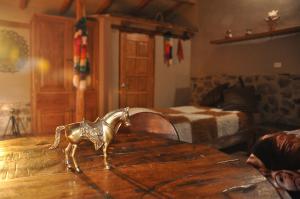 una figurita metálica de caballo sobre una mesa de madera en Valle Dorado Lodge en Cuzco