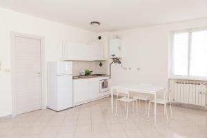 una cucina bianca con tavolo e sedie bianchi di Cornigliano Apartment 3 a Genova