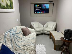 uma sala de estar com um sofá e uma televisão em Dith's House em Campos do Jordão