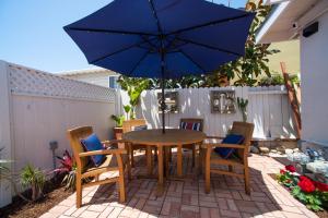 a table and chairs with a blue umbrella on a patio at La Jolla Windansea Luxury Apt in San Diego