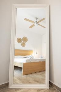 een spiegel in een slaapkamer met een bed en een plafondventilator bij Minimalist apartment near the airport and the city center in Kanálion