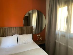 1 dormitorio con cama con espejo y ventana en Αura Luxury Apartments, en Ierissos