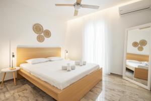 een witte slaapkamer met een groot bed en een spiegel bij Minimalist apartment near the airport and the city center in Kanálion