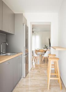 een keuken en eetkamer met witte kasten en houten krukken bij Minimalist apartment near the airport and the city center in Kanálion +4 foto's