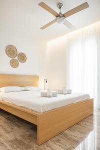 een slaapkamer met een groot bed met een plafondventilator bij Minimalist apartment near the airport and the city center in Kanálion