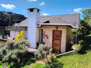 a small brick house with a tower on a yard at Chalés Lanelli in Monte Verde