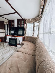 um sofá sentado numa sala de estar com televisão em Domki Parkowy em Kudowa-Zdrój