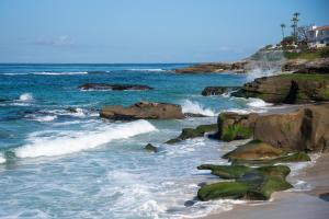 a beach with rocks and the ocean with waves at La Jolla Windansea Luxury Apt in San Diego