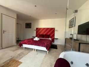 a bedroom with a red bed and a tub and a tub at La Suite Love de l Écu in Villeneuve-sur-Yonne