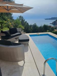 a swimming pool with chairs and an umbrella next to it at Lux Apartment Luna in Sveti Stefan