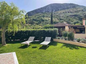 a yard with two chairs and a house with a mountain at Stefanos Home in Katelios
