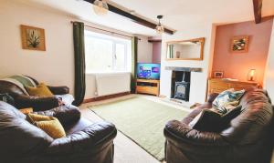 ein Wohnzimmer mit 2 Ledersofas und einem TV in der Unterkunft THE OLD WASH KITCHEN - Charming Character Cottage in Holmfirth, Yorkshire in Holmfirth