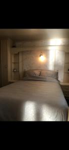 a bedroom with a white bed with a light on it at Stacaravan Het Zicht in Scherpenisse