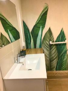 La salle de bains est pourvue d'un lavabo et d'une fresque murale représentant des feuilles. dans l'établissement VUE LAC LODGES, à Sévrier