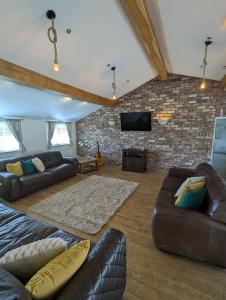 a living room with leather furniture and a brick wall at The Stables at Wits End, Hartford in Hartford +15 photos