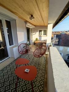 a balcony with red tables and chairs and a table at Appartement plein centre avec terrasse in Lons-le-Saunier